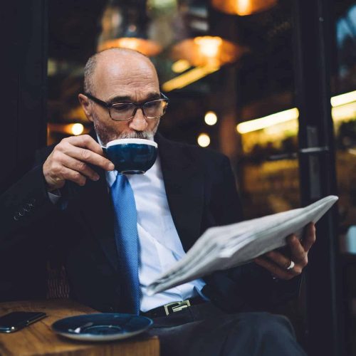 Senior businessman drinking coffee and reading newspaper